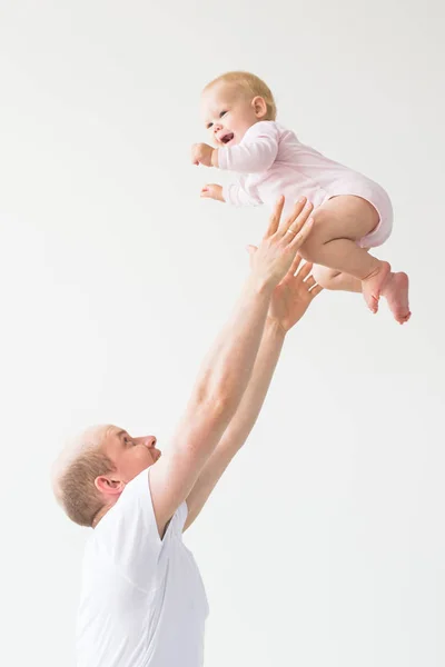 Father lifting baby girl. Happy father picks up and throws his lifting a small child. Home atmosphere, happy family laughing baby
