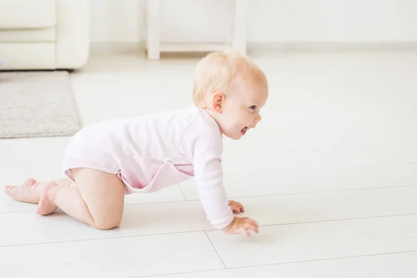 Childhood, children and babyhood concept - crawling funny baby girl indoors at home — Stock Photo, Image