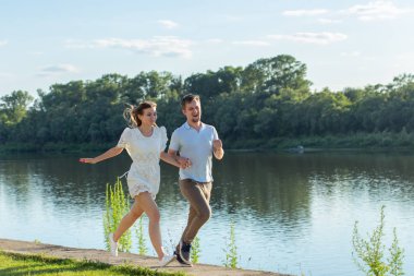 Aşk ve ilişki kavramı - mutlu erkek ve kadın bir göl yakınındaki bir parkta çalışan