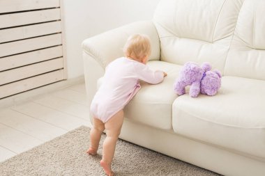 Çocuklar, bebek ve çocukluk konsepti - Güzel sevimli yumuşak bebek oturma odasında oynarken