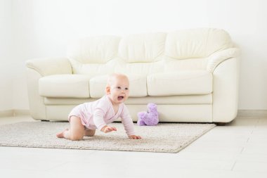 Sevimli bebek kız beyaz güneşli odada sürünmek öğrenme.