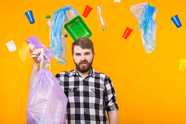 Plastic recycling problem, ecology and environmental disaster concept - Angry man holding garbage bag on yellow background