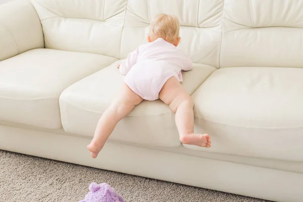 Concepto de la infancia, la infancia y la gente - niña feliz jugando cerca del sofá en casa — Foto de Stock