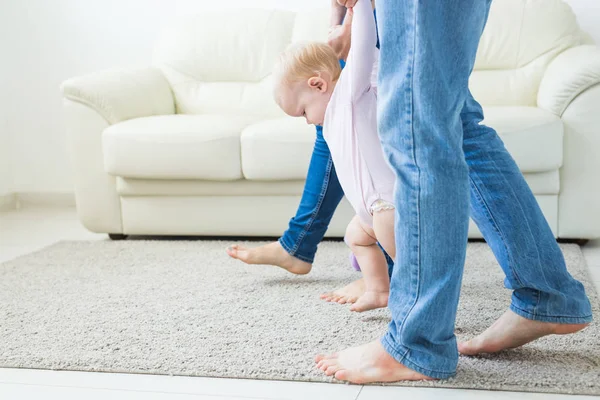 Primeros pasos del bebé pequeño aprendiendo a caminar en la sala de estar soleada blanca. Calzado para niños . — Foto de Stock