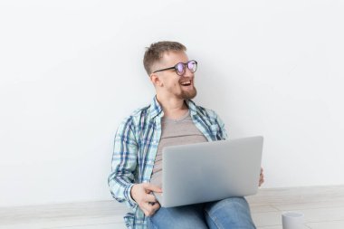 Rahat giysiler ve gözlük Internet Wi-Fi ve Kiralık Konut arayışı içinde bir dizüstü bilgisayar kullanarak sörf olumlu genç adam. Ev ve daire arama konsepti.