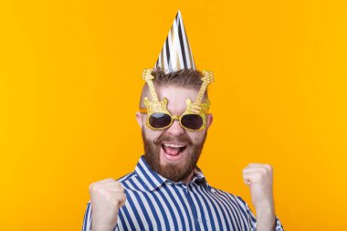 Bir kağıt kap ve gözlük joyful genç hipster erkek kopya alanı ile sarı bir arka plan üzerinde mutlu gülüyor. Bir mega parti ve tatil kavramı.