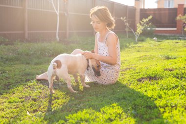 Onu Jack Russell Terrier köpek ile genç kadın dışarıda çim üzerinde oynuyor
