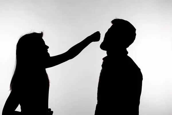 Concept d'agression et de maltraitance - homme et femme exprimant la violence domestique dans une silhouette de studio isolée sur fond blanc . — Photo