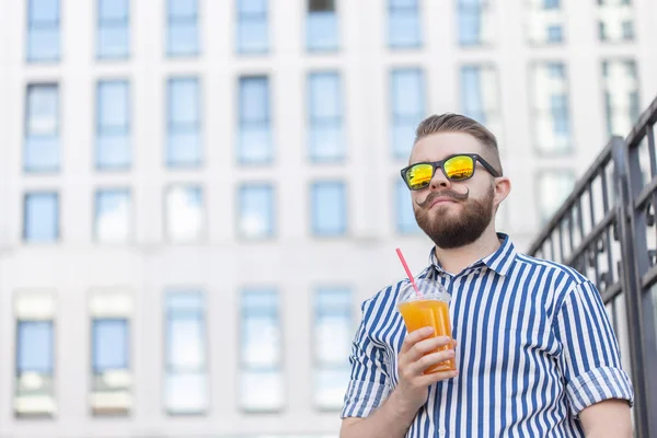 Bottom View portret van een stijlvolle jonge hipster man in spiegel glazen met SAP op de achtergrond van het Business Center. Urban Holiday in het weekend concept. — Stockfoto