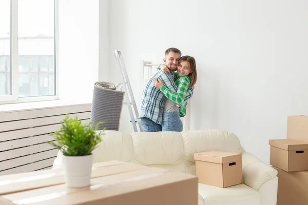 Liefdevolle jonge paar omarmen verheugen zich in de verhuizing naar hun nieuwe huis. Het concept van verhuizen en Inwijdingsfeest van jonge familie. — Stockfoto