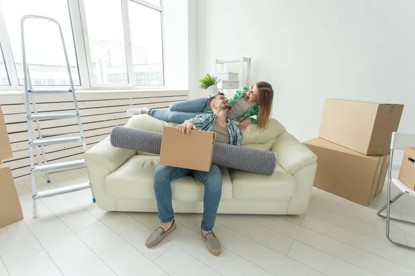 Alegre pareja joven se regocija en mudarse a una nueva casa que pone sus pertenencias en la sala de estar. Concepto de inauguración de casas e hipotecas para una familia joven —  Fotos de Stock