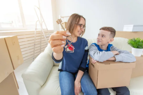흐릿한 긍정적 인 엄마와 아들이 소파에 앉아 새 아파트의 열쇠를 보여주고 있습니다. 신용 및 집들이에 주택 구매의 개념. 단일 부모 — 스톡 사진