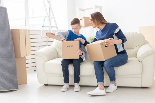 Милая мать-одиночка и маленький мальчик-сын сортируют коробки с вещами после переезда. Концепция ипотеки на новоселье и радость от нового жилья . — стоковое фото