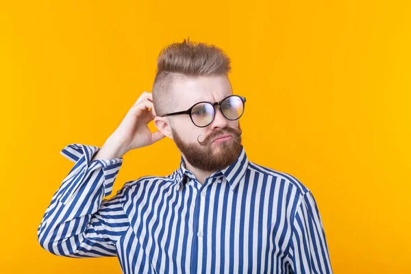 Aranyos intelligens fiatalember, a szakálla és a szemüveg jelent a sárga háttér, és úgy gondolja, valamiről. A nehéz választás fogalma. — Stock Fotó