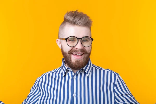 Joven hombre de moda positivo hipster con una barba bigote en camisa posando sobre un fondo amarillo . — Foto de Stock