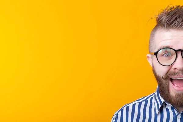 Elegante giovane hipster uomo con i baffi e la barba apre gioiosamente la bocca su uno sfondo giallo con spazio copia. Concetto di sorpresa e celebrazione. Copyspace . — Foto Stock
