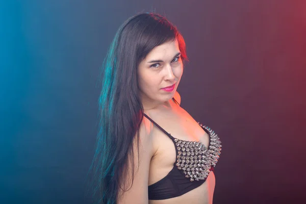 Attractive young sexy brunette woman in riveted top posing in the studio on a dark background. Concept of well-groomed young woman. — Stock Photo, Image