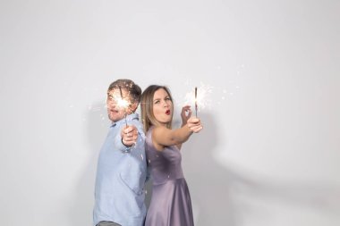 İnsanlar, parti ve kutlamalar kavramı - sırt sırta beyaz arka plan üzerinde kalan havai fişekleri ile genç Çift