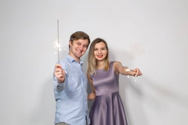 Kutlama, eğlence ve tatil kavramı - mutlu erkek ve kadın bir havai fişek sopa veya havai fişekleri tutun