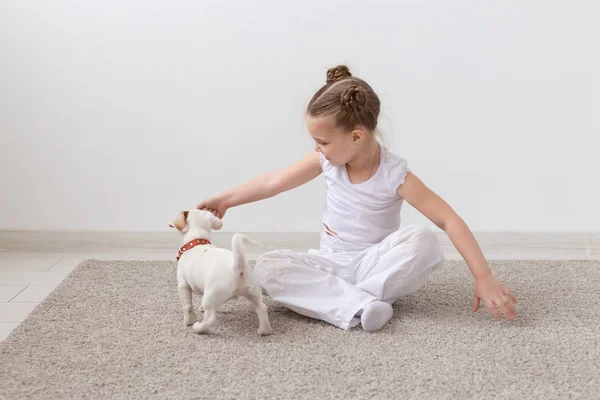 Mascotas, niños y concepto animal - Niña encantadora sentada en el suelo y alimentando al cachorro — Foto de Stock