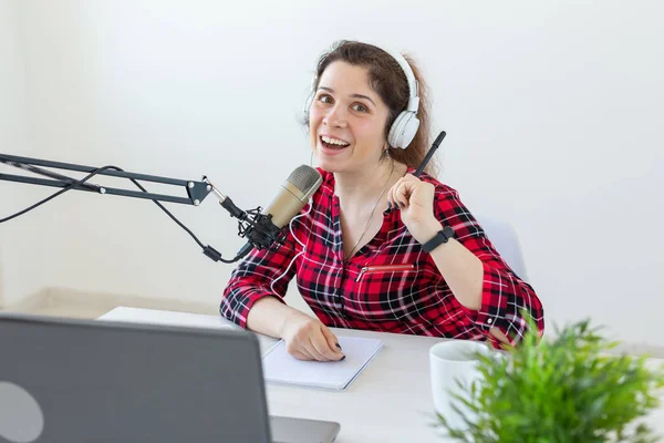 Radio host concept - Woman working as radio host sitting in front of microphone over white background in studio — Stock Photo, Image