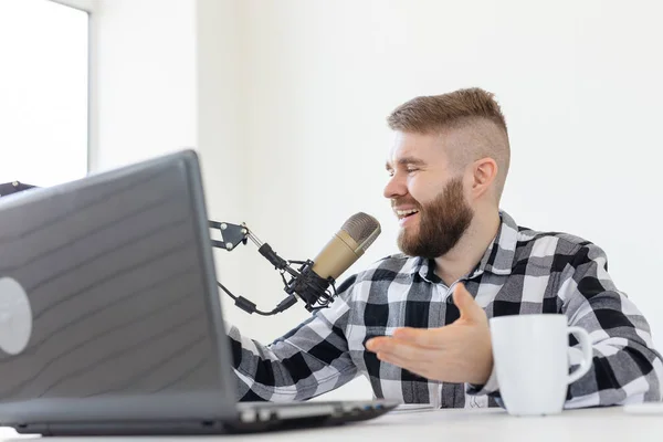 Radio, DJ, blogging and people concept - Smiling man sitting in front of microphone, host at radio