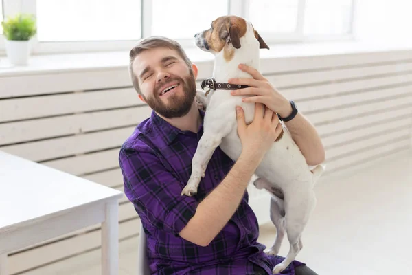 People, pets and home concept - young man playing with jack russell terrier puppy — Stock Photo, Image