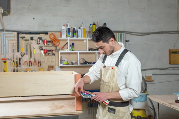 Jonge bebaarde man werken bij de meubelfabriek, kleur matching voor meubels — Stockfoto