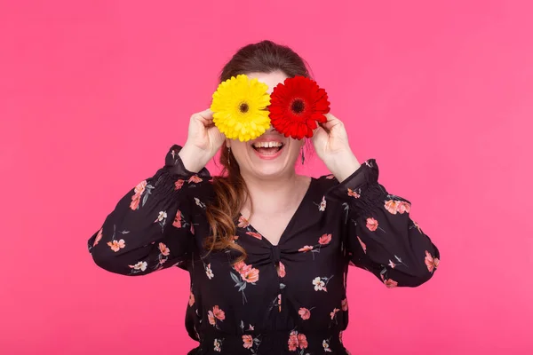 Flowers, emotions and people concept - woman closed her eyes with gerberas on pink background