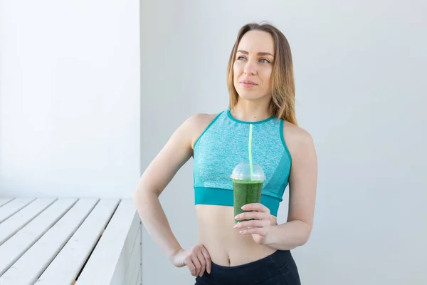 Healthy, sport, diet and people concept - Successful fitness urban woman recommending detox smoothie