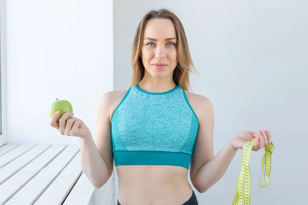 Stile di vita sano, dieta, perdita di peso e concetto di persone donna fitness con metro e mela sorridente felice guardando la fotocamera — Foto Stock