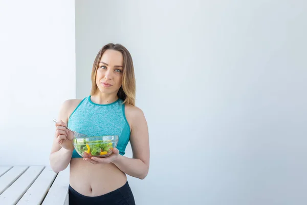 Stile di vita sano, fitness e dieta concetto - insalata alimentare e donna in abbigliamento sportivo, copyaspace — Foto Stock