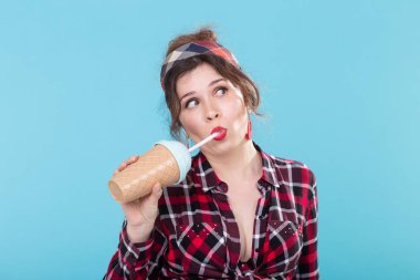 Gıda, diyet ve eğlenceli konsept - pin-up kadın mavi arka plan üzerinde kahve veya kokteyl içme