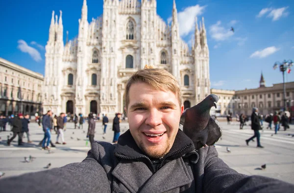 Kış seyahat, tatil ve kuşlar kavramı - yakışıklı erkek turist Milano'da ünlü Duomo Katedrali önünde selfie fotoğraf yapma komik güvercinler ile.