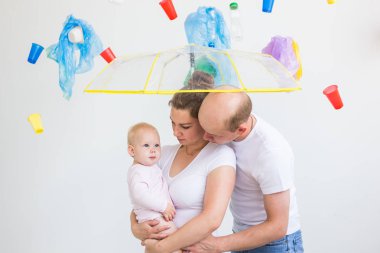Dünya Çevre Günü, plastik geri dönüşüm sorunu ve çevre felaketi kavramı - Üzgün aile beyaz arka plan üzerinde bir şemsiye altında çöpten gizleme