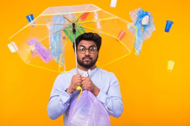 Çevre kirliliği, plastik geri dönüşüm sorunu ve ekoloji sorunu kavramı - üzgün hint adam sarı arka plan üzerinde çöp torbası tutan.