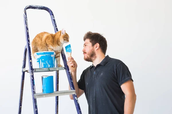 Renovation, redecoration and family concept - Young man stroking a cat during renovation in apartment — Stock Photo, Image