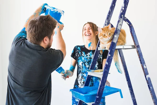 Mensen, renovatie, huisdier en reparatie concept - portret van mooie grappige paar met kat doen Pans in appartement — Stockfoto