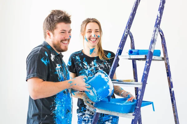 Επισκευή, ανακαίνιση και άνθρωποι έννοια - ζευγάρι που πρόκειται να βάψετε τον τοίχο, ετοιμάζουν το χρώμα και βούρτσες — Φωτογραφία Αρχείου