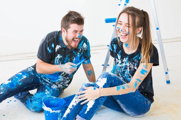 Concept de personnes, rénovation et intérieurs - Jeune couple assis sur le sol blanc et amusez-vous à la pause — Photo