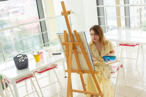 Umělecké umění, vysoká škola umění, vzdělávání pro skupinu mladých studentů. Šťastná mladá žena se usmívá, dívka se učí malovat. — Stock fotografie