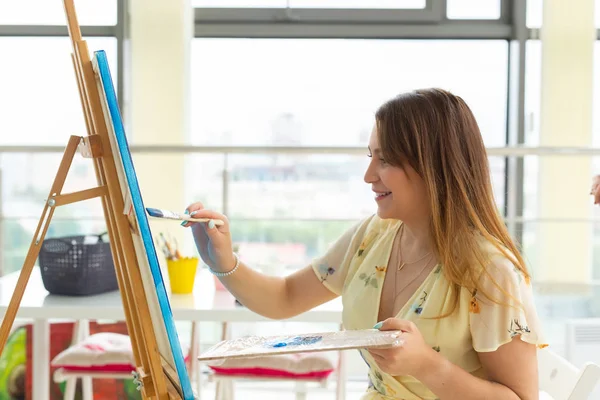 Lezione d'arte, disegno e creatività - Studentessa seduta davanti al cavalletto con tavolozza e pennello — Foto Stock