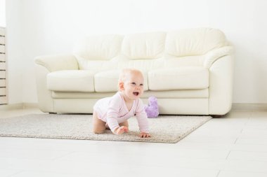 Yerde evde gülümseyen sürünen bebek kız