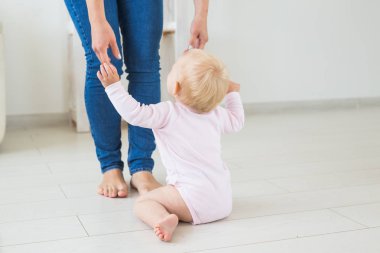 Küçük emekleme kız kız bir yaşında parlak ışık oturma odasında katta gülümseyerek ve gülüyor oturuyor. Evde oynayan mutlu bir çocuk. Çocukluk kavramı