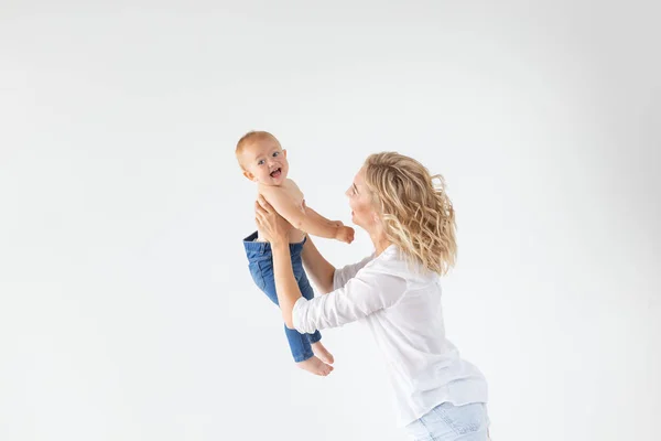 Tek ebeveyn, annelik ve bebek kavramı - Neşeli anne stüdyoda küçük kızı ile eğleniyor, beyaz arka plan üzerinde izole — Stok fotoğraf
