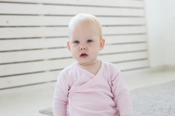 Kindertijd, kinderen en babyhood concept-schattige blonde baby zittend op de vloer — Stockfoto