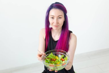 Fiziksel eğitim den sonra hafif bir yunan salatası yeme renkli saçlı Pozitif karışık ırk hipster kız. Doğru beslenme ve kilo kaybı kavramı.