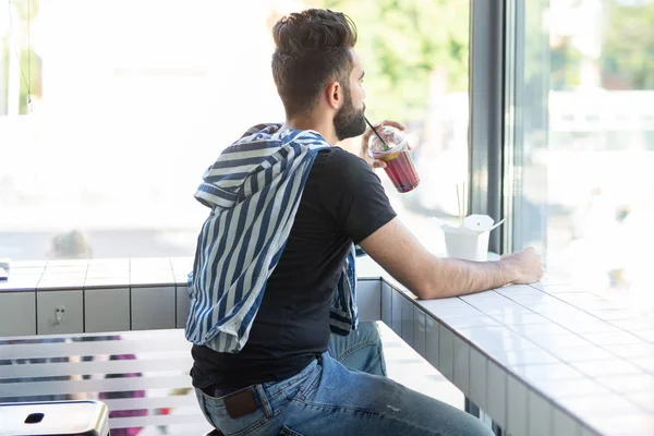Pozitif genç şık adam iş yerinde bir mola sırasında bir kafede suyu içme. Dinlenme ve sağlıklı atıştırmalık kavramı.