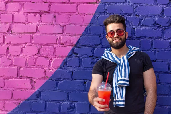 Şık bir bıyık ve elinde meyve suyu ile bir sakal ile yakışıklı neşeli genç arap öğrenci, bir iş gününden sonra şehir etrafında yürüyüş. Pozitif ve dinlenme kavramı.