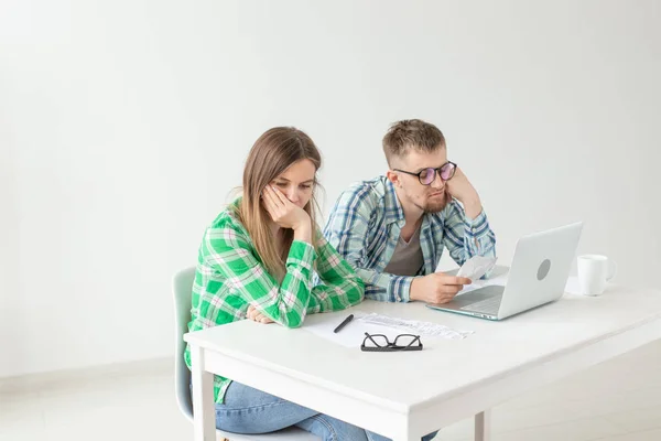 Husband and wife discuss amount in check for payment of the apartment and compare it with the rates on official website while sitting at the table with laptop. Concept of payment of utility bills.